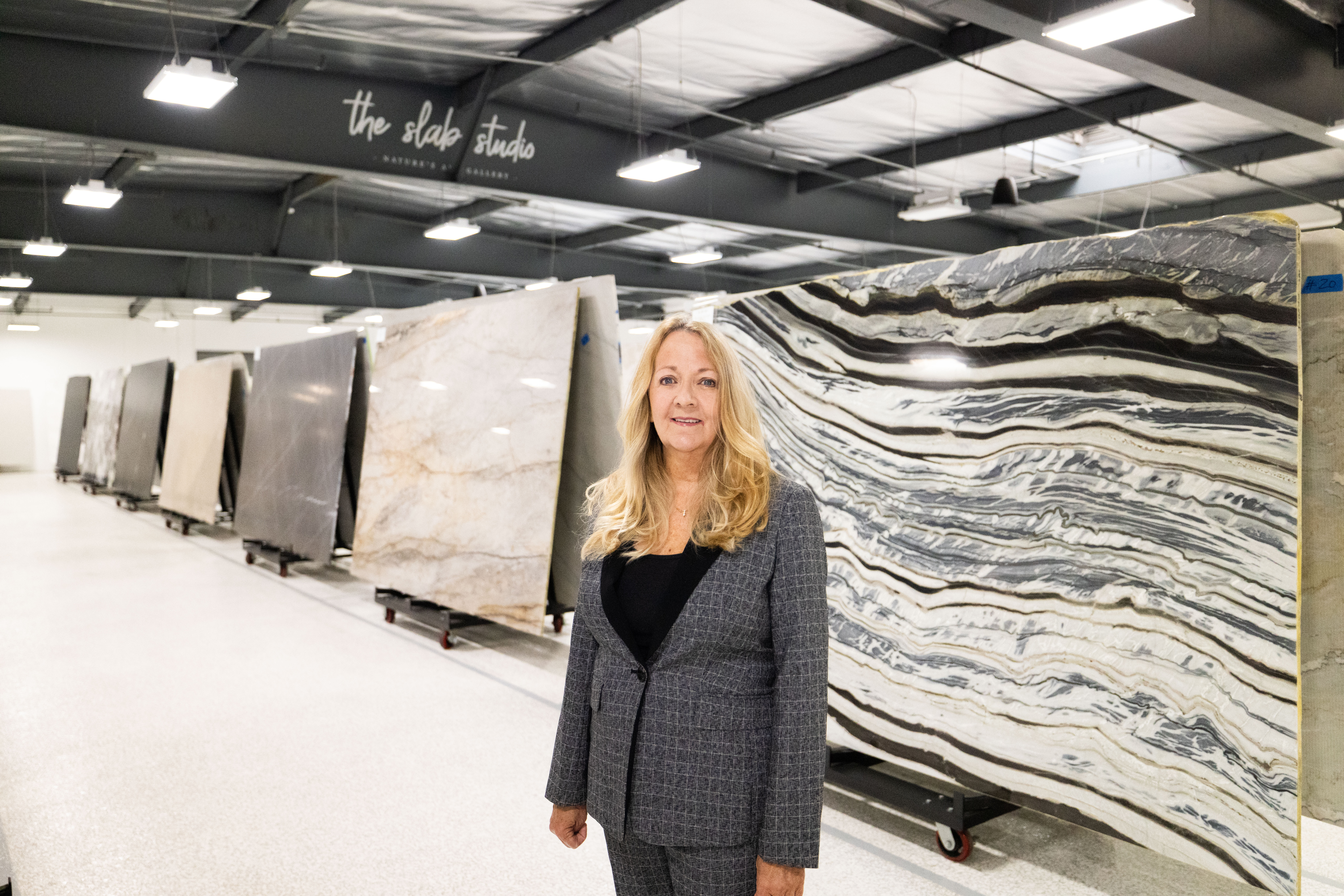 Jill Carroll standing beside premium natural stone slabs at The Slab Studio gallery.