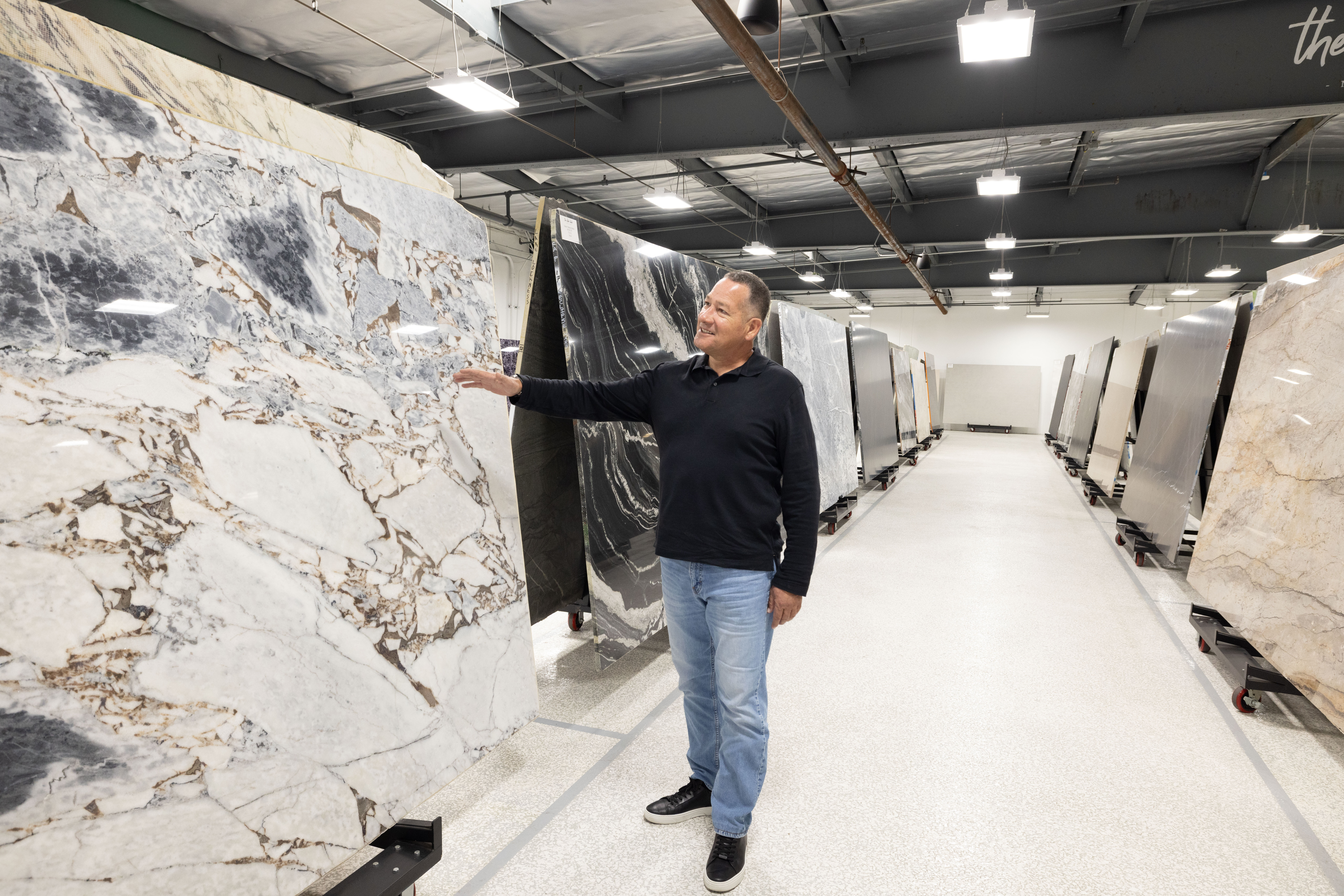 Josiah Inspecting Premium Stone Slab Josiah examining a premium natural stone slab inside The Slab Studio showroom in Santa Ana, California.