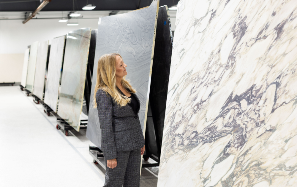 Jill Kummer reviewing a dramatically veined natural stone slab at The Slab Studio showroom in Santa Ana, California.