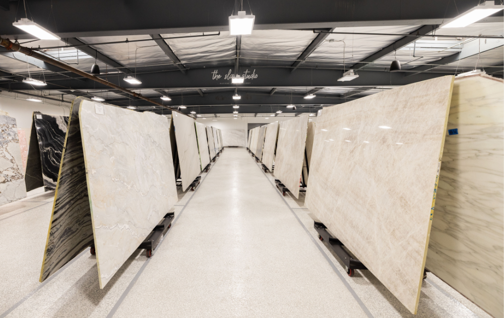 Wide view of The Slab Studio's indoor natural stone slab showroom in Santa Ana, featuring premium slabs displayed under professional lighting.