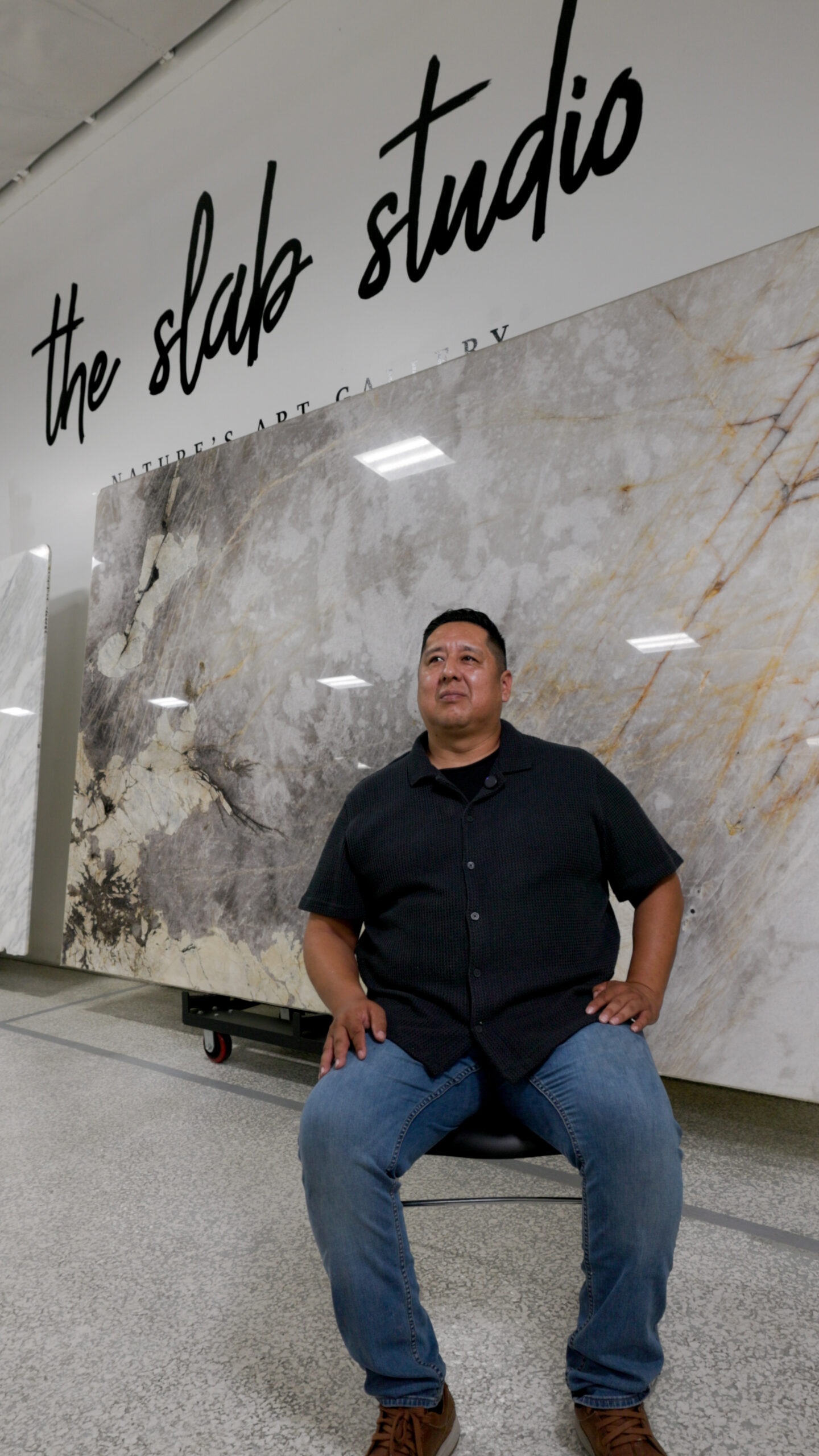 Abraham De Rosas of NCD Artisan Stone standing beside a Patagonia Quartzite slab at The Slab Studio showroom in Santa Ana, California.